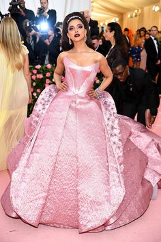 a woman in a pink gown standing next to other people