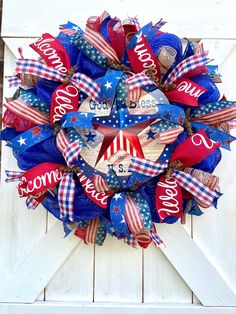 a patriotic wreath on a white door with red, white and blue ribbons around it