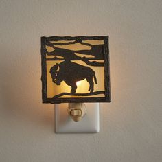 a light that is on the wall with a cow in it's shadow,