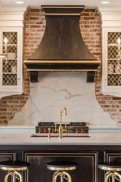 a kitchen with an oven and two stools in front of the counter top that has gold accents