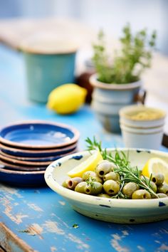 a bowl filled with olives on top of a blue table