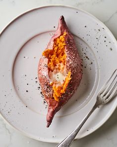 a white plate topped with a piece of meat covered in cheese and spices next to a fork