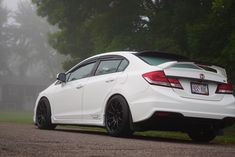 the rear end of a white honda civic hatchback parked on a foggy road