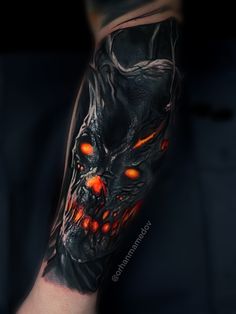 a man's arm with a black and red tattoo design on it, depicting an evil demon