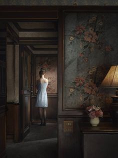 a woman in a white dress is looking into a room with flowers on the wall