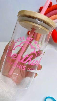 a person holding a cup with some pink writing on it and a pair of scissors