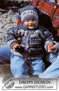 a young child sitting on the ground next to an older man wearing a knitted hat