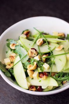 a white bowl filled with green vegetables and nuts