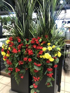 two black planters with red and yellow flowers in them