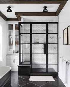 a black and white bathroom with glass shower doors