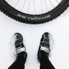 a person standing next to a bike tire in the snow