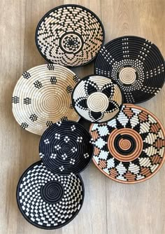 woven baskets are arranged on the floor in different patterns and sizes, with one black and white basket at the center