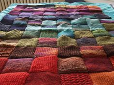 a multicolored knitted blanket sitting on top of a bed next to a radiator