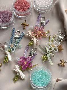 there are many beads in small containers next to each other on the table with scissors