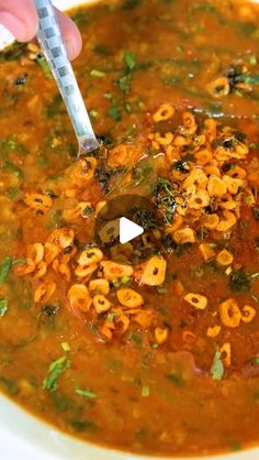 a spoon in a bowl filled with soup and some sort of food on the side