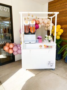 a small ice cream stand with balloons and confetti hanging from it's sides