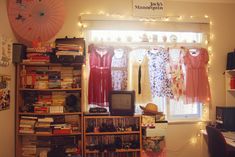 a room filled with lots of books and various items on the shelves next to a window