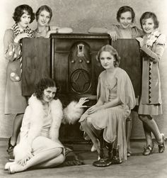 an old black and white photo of four women sitting in front of a vintage radio