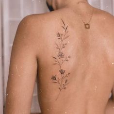 the back of a woman's body with flowers tattooed on her upper and lower back