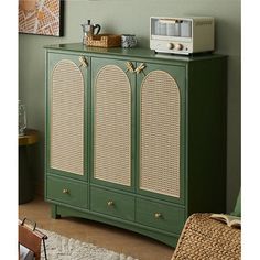 a green cabinet with wicker doors and drawers in a room next to a rug