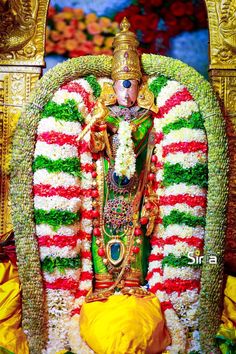 an idol is sitting in the middle of a stage decorated with flowers and garlands