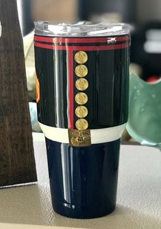 a blue cup with gold coins on it sitting on a table next to a piece of wood