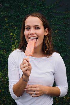 a woman holding up a piece of food in her right hand and smiling at the camera