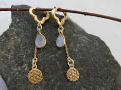 brass gold-plated earrings, featuring a stunning drop moonstone that radiates elegance. The intricate round flower of life symbol dangles gracefully, adding a touch of spiritual significance and artistic flair. Perfect for both casual and formal occasions, these earrings are a must-have for those who appreciate unique and meaningful jewelry. Flower Of Life Symbol, Round Flower, Life Symbol, Earrings Flower, Meaningful Jewelry, Moonstone Earrings, Brass Gold, Flower Of Life, Brass Earrings