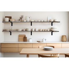 a table with plates and bowls on it in front of a wall filled with shelves