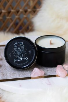 a candle sitting on top of a table next to some pink rocks and crystals in front of it