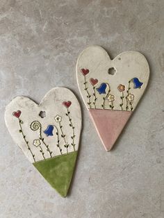 two ceramic heart shaped ornaments with flowers on them