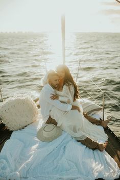 a man and woman sitting on the back of a boat in the ocean hugging each other