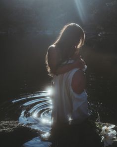 a woman standing in the water with her arms around her back