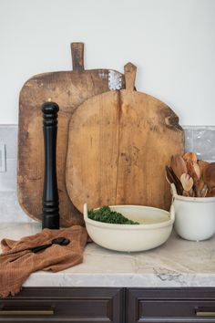 a wooden cutting board sitting on top of a counter next to bowls and utensils