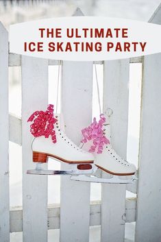 a pair of ice skates with pink bows hanging from them on a white fence