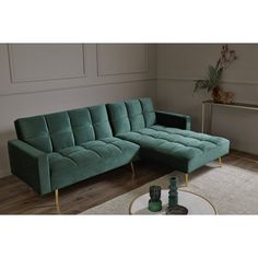 a green sectional sofa sitting on top of a wooden floor next to a white rug