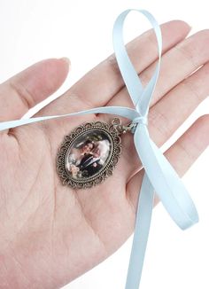 a person's hand holding a small pendant with a blue ribbon around it