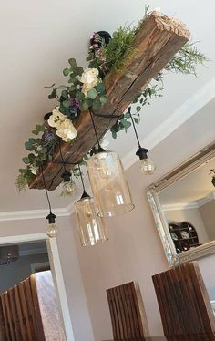 a wooden beam with flowers and greenery hanging from it's ceiling in a dining room