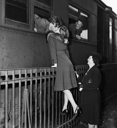 an old photo of two women standing on the side of a train as another woman leans against the rail