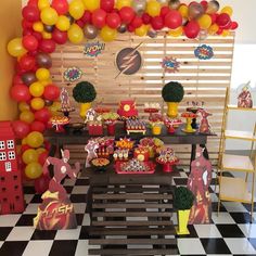 a party with balloons and decorations on the wall, including an iron man cake table