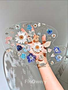 a person holding a glass plate with flowers on it