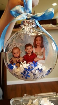 a christmas ornament with two babies in it and snowflakes on the bottom