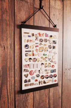 a wooden wall with a poster hanging from it's side and lots of different badges on it