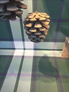 a pine cone hanging from the ceiling in front of a checkered wallpapered room