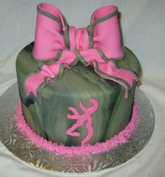 a green cake with pink decorations and bows on the top is sitting on a silver platter