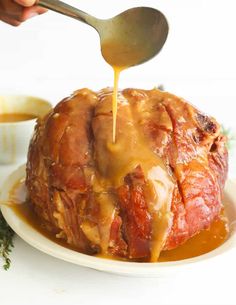 someone is pouring sauce on a meatloaf covered in gravy and sitting on a white plate