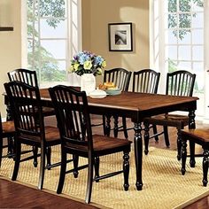 a dining room table and chairs in front of a window with flowers on the table