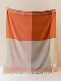 an orange and white blanket hanging on a wall