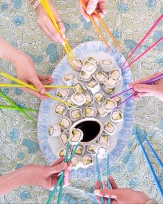 several people holding chopsticks over a plate with sushi and rolls on it