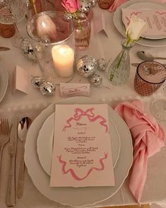 the table is set with silverware, pink napkins, and white dinnerware